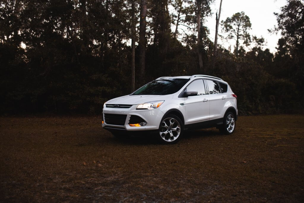 white suv in front of trees